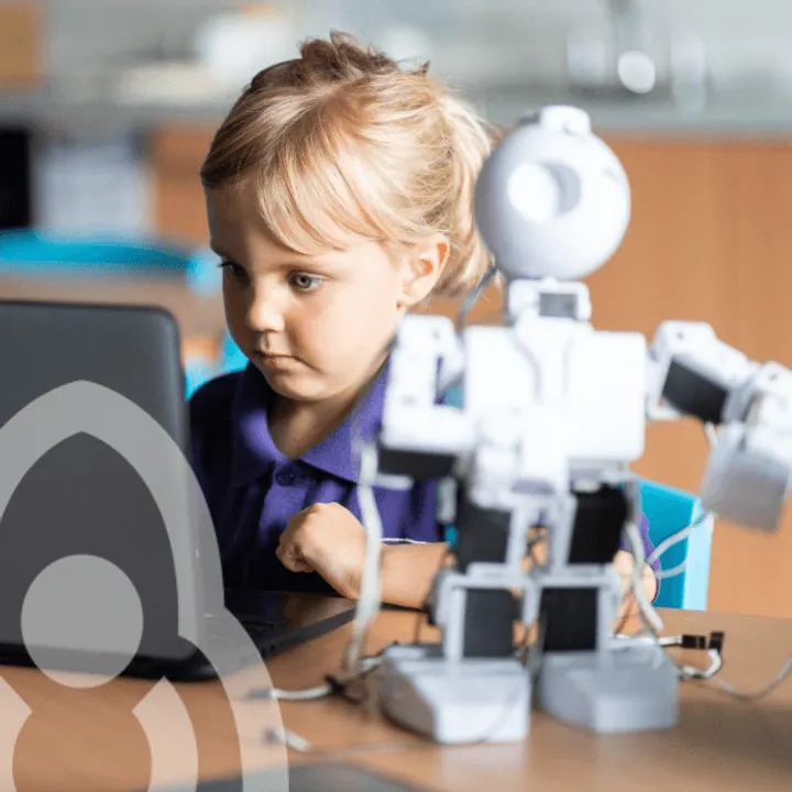 A primary-school pupil at a laptop, building and programming a small humanoid robot.