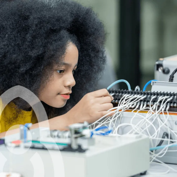 A student concentrating as they wire up a piece of electronic lab equipment.